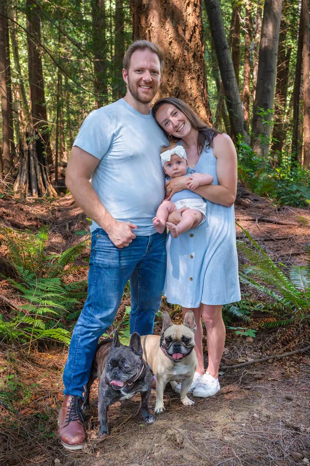 family posing in the forest with their dogs